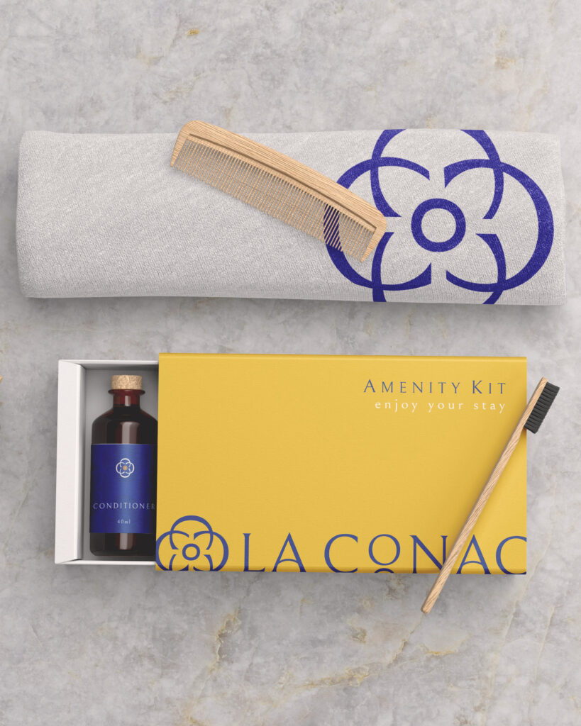 La Conac amenity kit featuring an embroidered towel, wooden comb, bamboo toothbrush, and artisanal conditioner, arranged elegantly to convey a premium guest experience. Kit de amenities de La Conac con toalla bordada, peine de madera, cepillo dental de bambú y acondicionador artesanal, presentado de forma elegante para una experiencia de hospedaje premium.